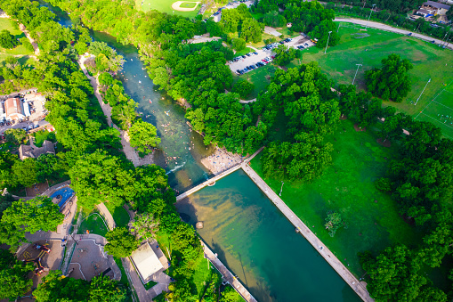 Aerial drone view looking down from above empty , no people,  Barton springs swimming pool a natural attraction of Austin Texas USA with green lush forest surroundings
