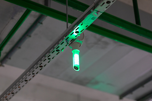 Green parking sensor on ceiling - free space. Smart parking concept, closeup.