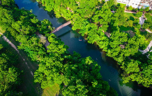 Austin Texas drone view above green paradise trees and clear waters of Barton springs with the Bridge crossing
