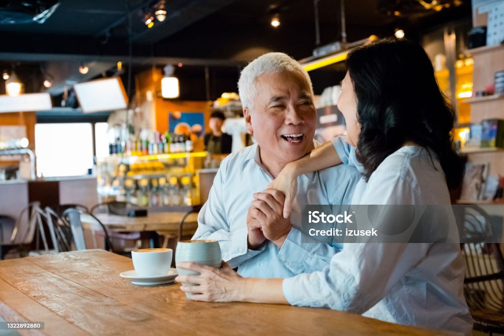 Senior couple enjoying coffee in cafe Senior woman and man sitting at the table in small cafe and drinking coffee. Asian couple enjoying time together. 60-69 Years Stock Photo