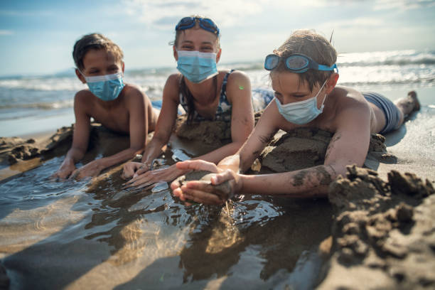 kinder spielen am strand während covid-19 pandemie - lifestyles child beach digging stock-fotos und bilder