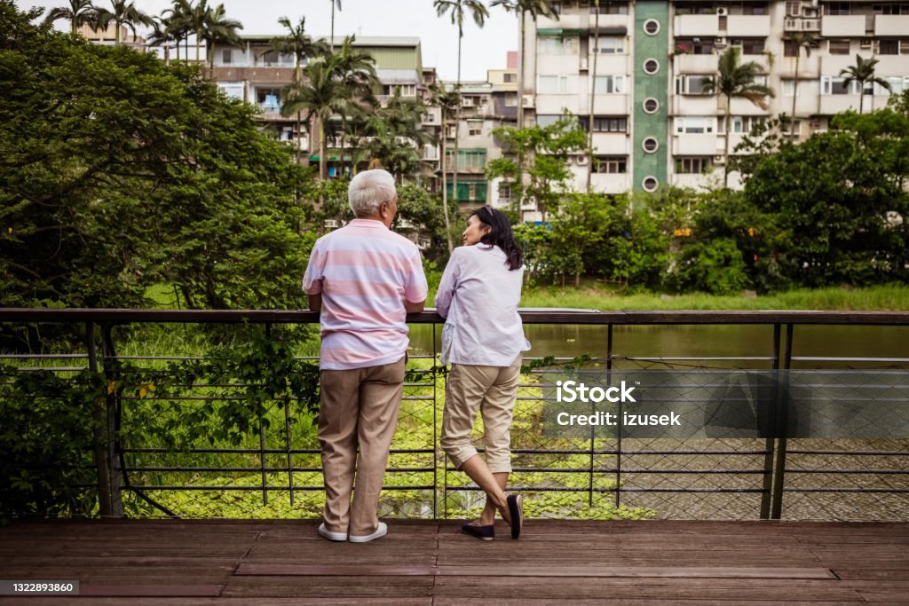 Senior couple relaxing in the park Back view of senior woman and man standing in the park in the cit. Asian couple enjoying time together. Friendship Stock Photo
