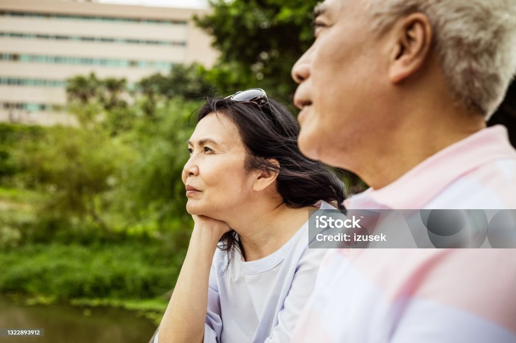 Senior couple relaxing in the park Senior woman and man sitting in the park in the city, close up of faces. Asian couple enjoying time together. Asia Stock Photo