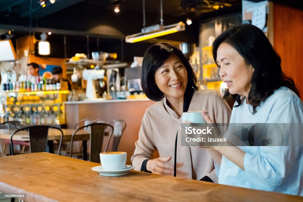 Senior friends enjoying coffee in cafe Senior women sitting at the table in small cafe over coffee. Asian friends enjoying time together. 60-69 Years Stock Photo