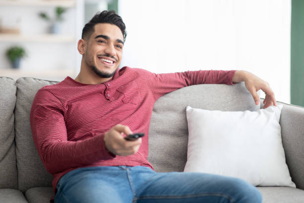 istock Relaxed middle-eastern guy switching channels on TV 1322895734