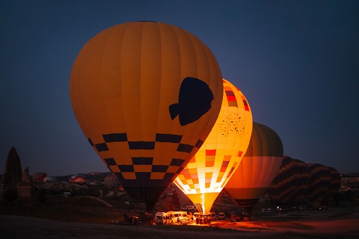 Hot air balloon is inflated in the early morning hours by a Latino man with an average age of 50 years who is the pilot in charge of providing this experience to tourists.