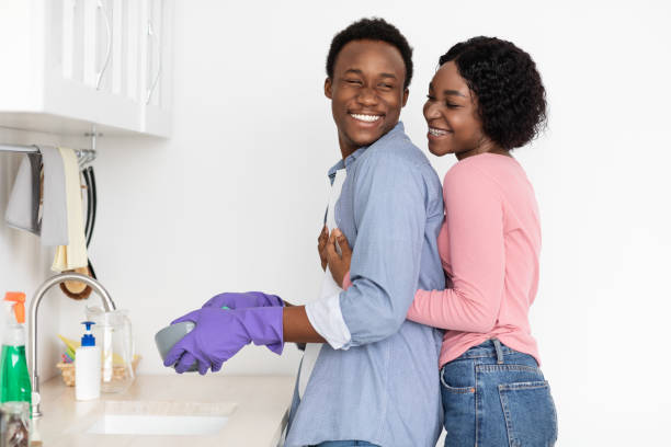 istock Black woman hugging her husband washing dishes 1322896026
