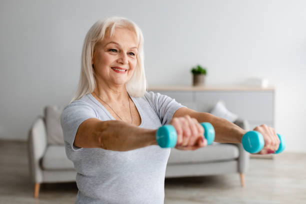 istock Mature woman exercising at home with two dumbbells 1322897145