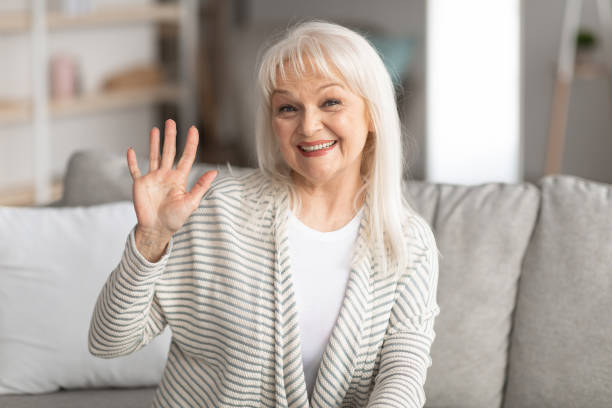 istock Mature woman waving at camera and smiling 1322897288