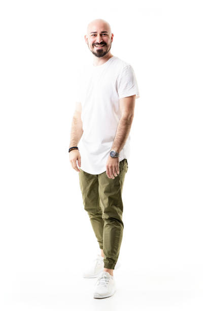 istock Smiling cheerful young bald bearded man in olive green chino pants. 1322897432