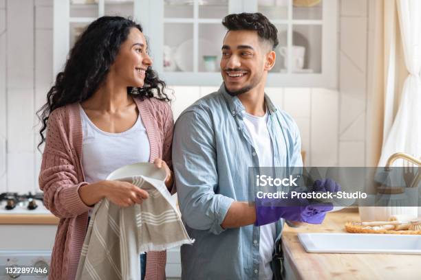 Cheerful Middle Eastern Couple Sharing Domestic Chores Washing Dishes Together In Kitchen Stock Photo - Download Image Now