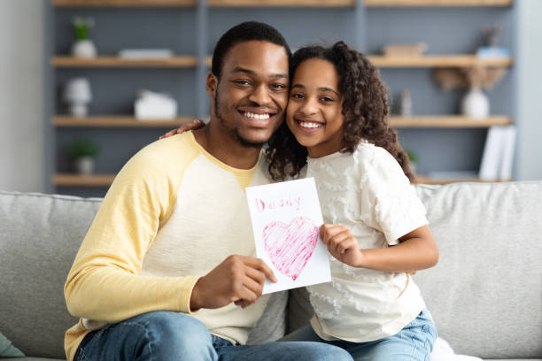 istock Cute black girl with gift card hugging her father 1322898764