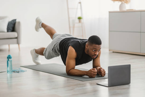 istock African Man Exercising At Laptop Doing Plank Leg Raises Indoor 1322899854