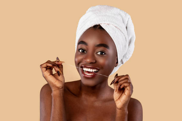 istock Young black woman using dental floss looking at camera 1322899881