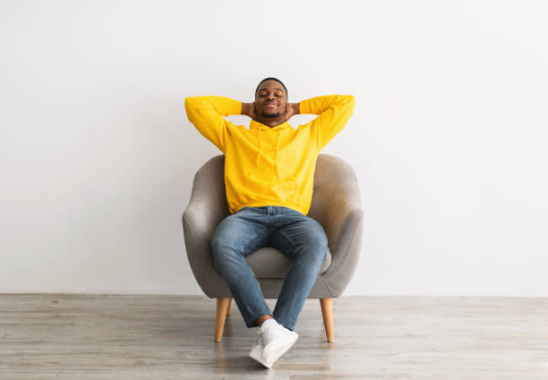istock Relaxed Black Man Resting Sitting In Chair Over Gray Background 1322899896