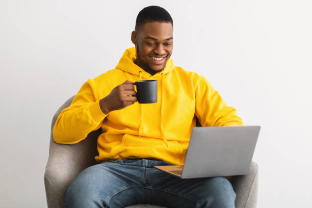 istock Happy African American Guy Using Laptop Drinking Coffee, Gray Background 1322900064