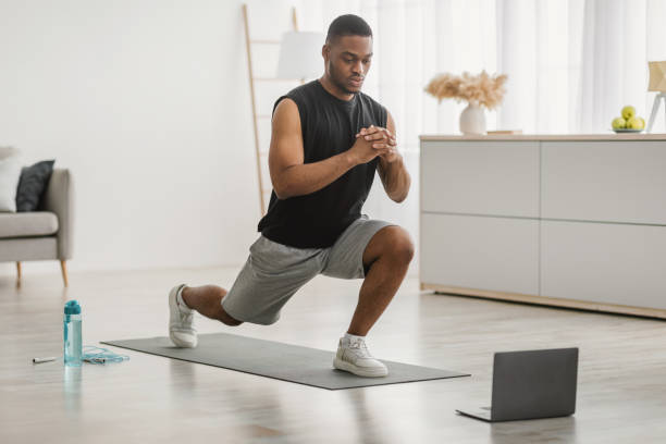 istock Black Guy Doing Forward Lunge Exercise At Laptop At Home 1322900654