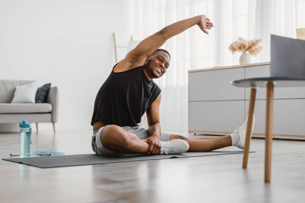 istock Cheerful Black Man Doing Side Bend Stretching Exercise At Home 1322900712