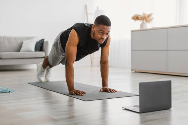 istock Sporty Black Guy Exercising At Laptop Doing Plank At Home 1322900740