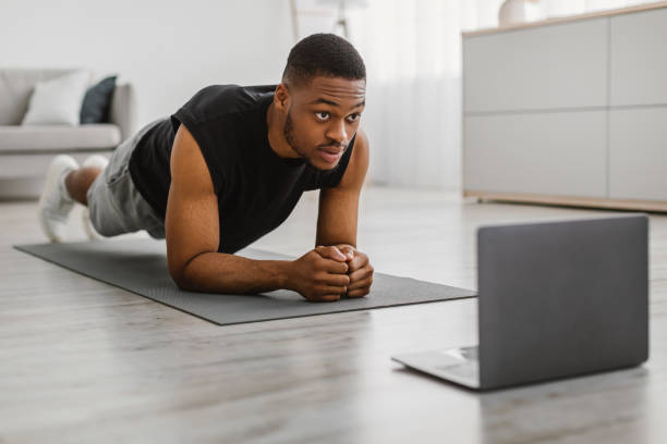 istock African Guy Doing Elbow Plank Exercise At Laptop At Home 1322901241