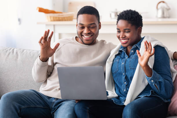 istock Black couple having videocall using laptop waving hands 1322901786