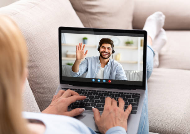 istock Distance communication. Young lady sitting on sofa with laptop, making video call, speaking to her boyfriend online 1322903840