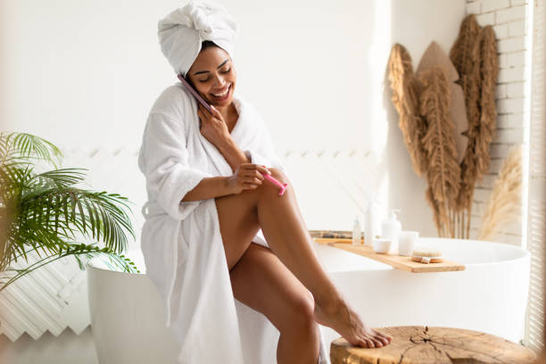 istock Cheerful African Lady Talking On Phone While Shaving Legs Indoor 1322904436