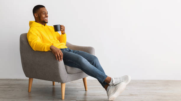 istock African Guy Drinking Coffee Sitting In Chair Over Gray Background 1322904488