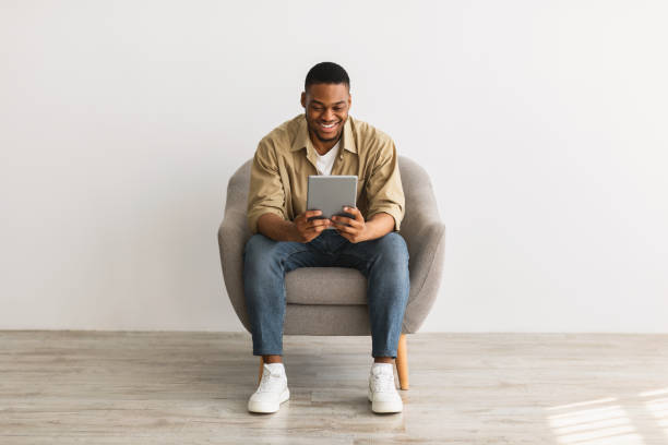 istock Happy African Man Using Digital Tablet Sitting Over Gray Background 1322904602
