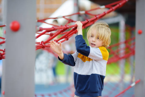 cute preschooler boy having fun on outdoor playground. spring/summer/autumn active sport leisure for kids. activity for children. equipment of entertainment park for kids. - 12007 imagens e fotografias de stock