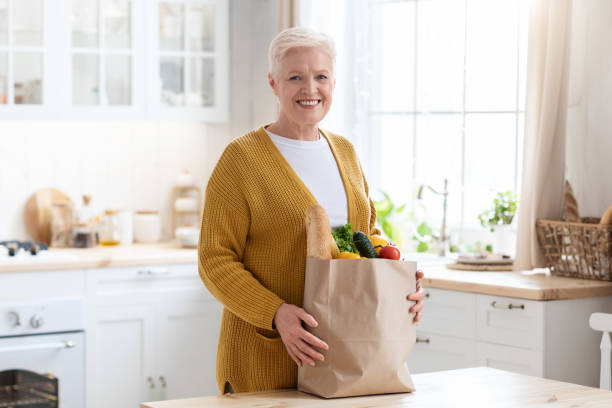 istock Smiling old woman with grocery bag ordered from internet 1322905085