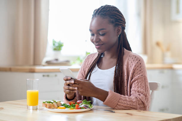 istock Happy Young Black Female Having Breakfast And Using Smartphone In Kitchen 1322907129