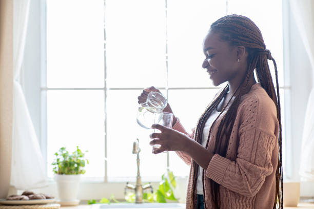istock Cheerful Young Black Lady Drinking Water In Kitchen At Home, Holding Jug 1322907328