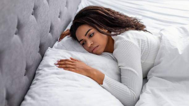 Depressed black lady lying in bed alone and feeeling upset Depression Concept. Portrait of unhappy young African American lady lying in bed alone and feeeling upset after breakup with her boylfriend or husband, hugging pillow. Sad woman feeling lonely horror waking up bed women stock pictures, royalty-free photos & images