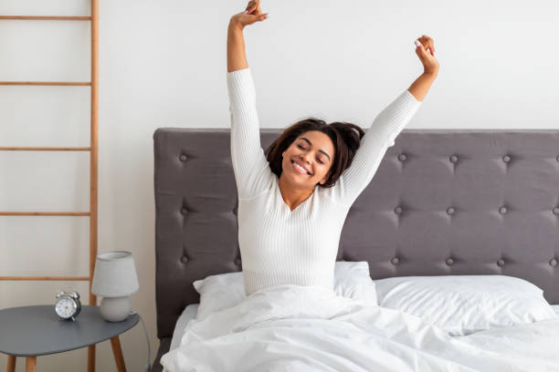 istock Peaceful black woman stretching arms and back sitting on bed 1322908466