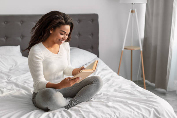 istock Black woman reading in bed and smiling 1322908501