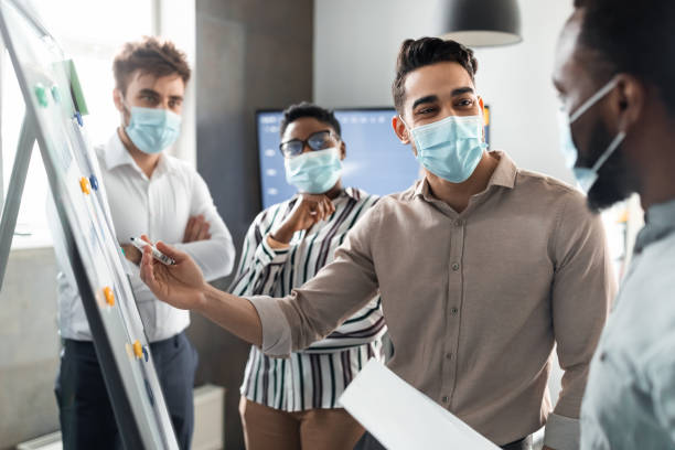 istock Man in protective medical mask presenting business strategy on whiteboard 1322908530