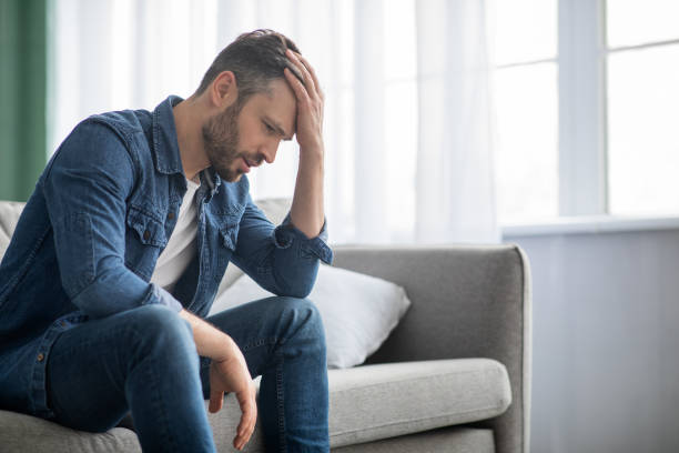 istock Pensive man sitting on couch at home, side view 1322908705