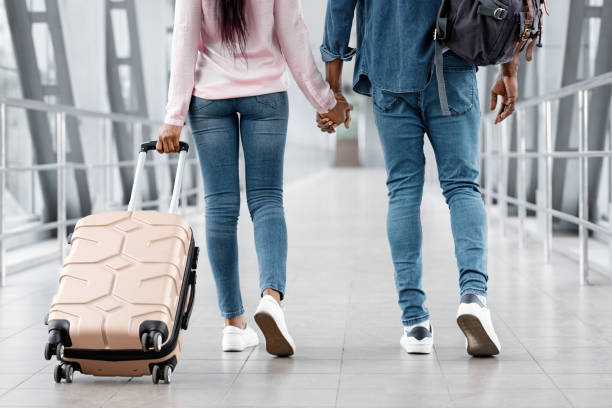 istock Ready For Vacation. Black Couple Holding Hands While Walking In Airport, Cropped 1322909383