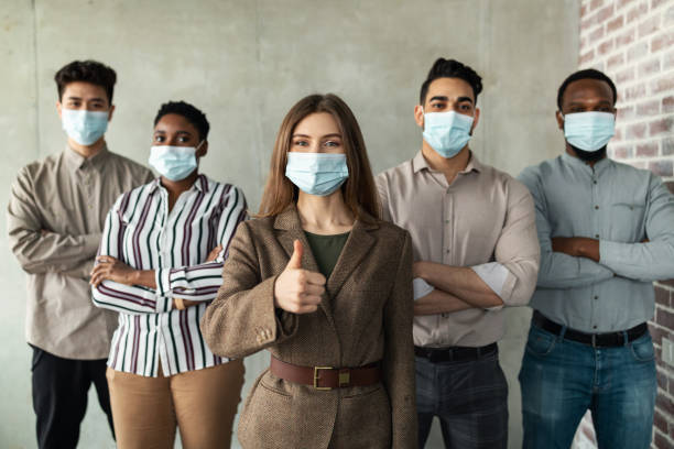 istock Multicultural businesspeople in masks standing in office with folded arms 1322910120
