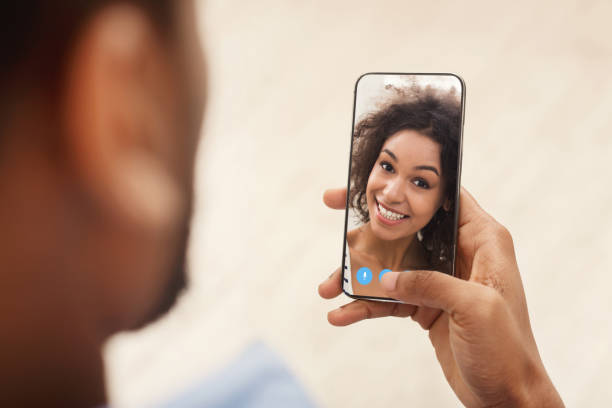 istock Distance Communication. Black guy with smartphone making video call to his girlfriend 1322911425