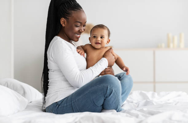 istock Black nanny sitting on bed with her cute baby 1322911556
