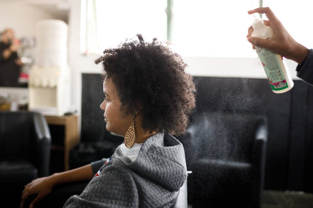 mano femminile che spruzza i capelli ricci della donna - capelli neri foto e immagini stock