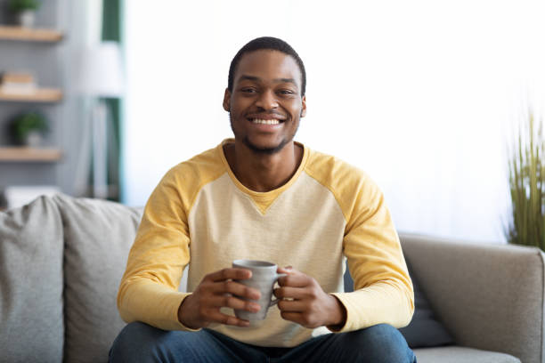istock Cheerful handsome black man drinking coffee in living room 1322916945
