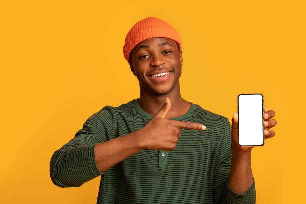 istock Happy Black Hipster Guy Holding And Pointing On Smartphone With White Screen 1322917077
