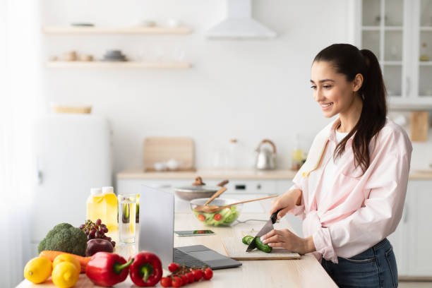 istock Woman cooking salad and using pc and kitchen 1322919965