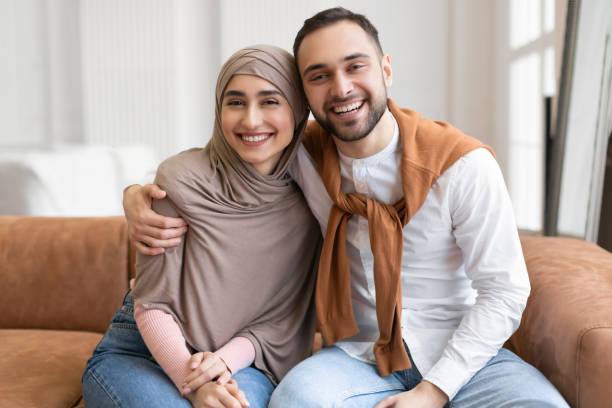 istock Joyful Muslim Spouses Smiling Hugging Sitting On Sofa At Home 1322920269
