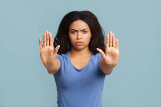 istock Stop concept. Serious black lady making stop hand gesture on blue studio background, selective focus 1322920459