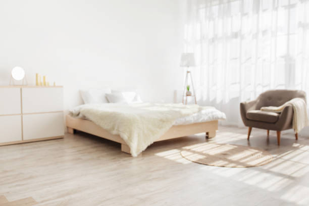 istock Stylish minimalist contemporary boho home interior. Double bed with pillows and blanket, furniture, lamp, armchair 1322920879