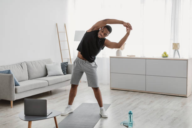 istock Black Guy Exercising Near Laptop Doing Side Bend Stretching Indoor 1322920994
